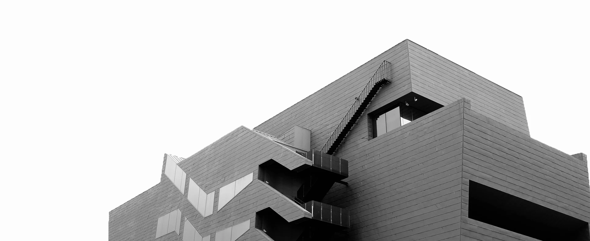 low-angle-greyscale-shot-concrete-modern-building-isolated-white-wall-